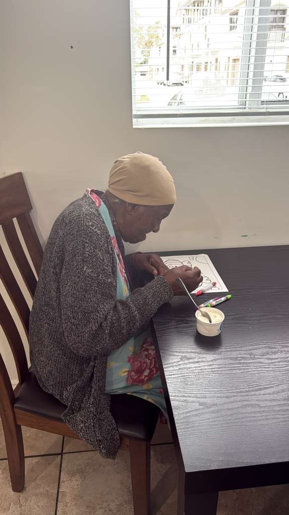 A resident quietly coloring by the window at Atlantis Senior Care Residence