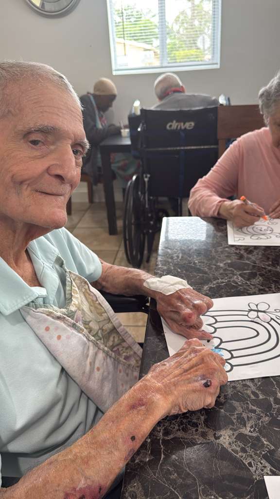 A resident smiling warmly during a group activity at Atlantis Senior Care Residence