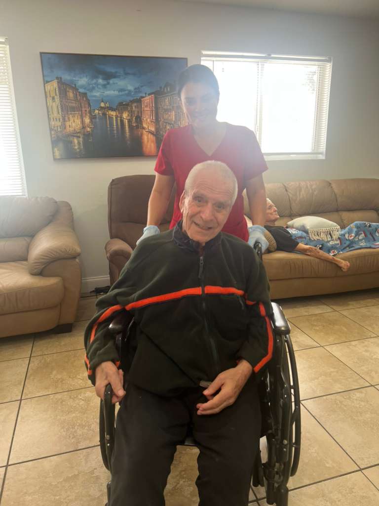A smiling caregiver assisting a resident through the Atlantis Senior Care Residence living room