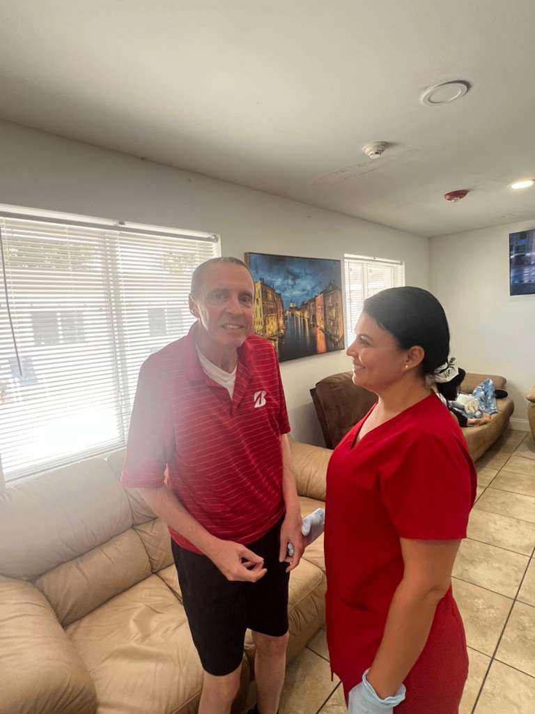 A caregiver warmly greeting a resident in the Atlantis Senior Care Residence common area